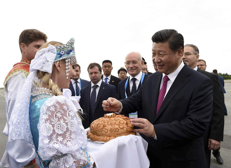7月8日，國家主席習近平乘坐專機抵達烏法，應俄羅斯聯(lián)邦總統(tǒng)普京邀請，出席金磚國家領導人第七次會晤和上海合作組織成員國元首理事會第十五次會議。這是在烏法國際機場，身穿俄羅斯民族服飾的青年按當?shù)赜淤F賓的傳統(tǒng)，向習近平敬獻面包和鹽。習近平掰下一小塊面包，蘸鹽品嘗。新華社記者 饒愛民 攝