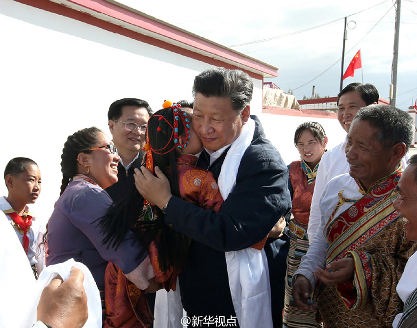 離開(kāi)長(zhǎng)江源村時(shí)，村裡男女老少排起長(zhǎng)長(zhǎng)隊(duì)伍，揮著哈達(dá)，高喊“總書(shū)記好”“扎西德勒”，依依不舍同總書(shū)記握手話別。一位由大人抱著的小姑娘向總書(shū)記獻(xiàn)上哈達(dá)，總書(shū)記輕輕親吻孩子的臉頰，希望她健康成長(zhǎng)。攝影/新華社記者蘭紅光、龐興雷