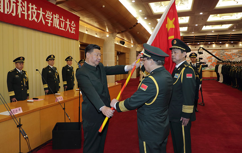 7月19日，新調(diào)整組建的軍事科學(xué)院、國防大學(xué)、國防科技大學(xué)成立大會暨軍隊(duì)院校、科研機(jī)構(gòu)、訓(xùn)練機(jī)構(gòu)主要領(lǐng)導(dǎo)座談會在北京八一大樓舉行。中共中央總書記、國家主席、中央軍委主席習(xí)近平向軍事科學(xué)院、國防大學(xué)、國防科技大學(xué)授軍旗、致訓(xùn)詞，出席座談會並發(fā)表重要講話。這是習(xí)近平將軍旗鄭重授予國防科技大學(xué)校長鄧小剛、政治委員劉念光。新華社記者 李剛 攝