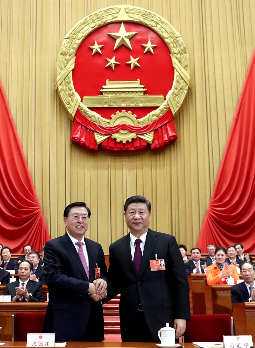 3月17日，十三屆全國(guó)人大一次會(huì)議在北京人民大會(huì)堂舉行第五次全體會(huì)議。習(xí)近平當(dāng)選中華人民共和國(guó)主席、中華人民共和國(guó)中央軍事委員會(huì)主席。這是習(xí)近平在主席臺(tái)上同十二屆全國(guó)人大常委會(huì)委員長(zhǎng)張德江握手。新華社記者 鞠鵬 攝