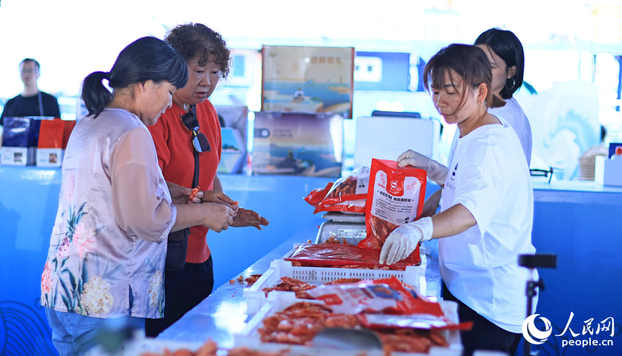 游客在澳角村采購當?shù)睾ｕr加工產(chǎn)品。人民網(wǎng) 李昌乾攝
